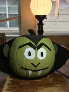 a pumpkin with an evil face on it sitting on a table next to a lamp