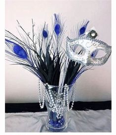 a vase filled with blue feathers and a mask