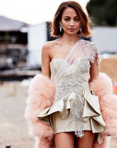 a model walks down the runway in a short dress with feathers on her skirt and heels