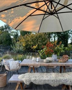 an outdoor dining table with two benches and umbrellas over it on a wooden deck