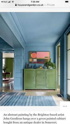 a living room with blue walls and green furniture in the center, along with an area rug on the floor