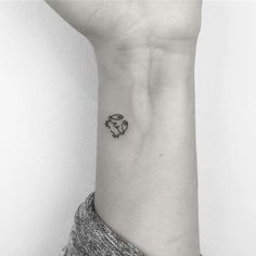 a black and white photo of a woman's wrist with a small tattoo on it