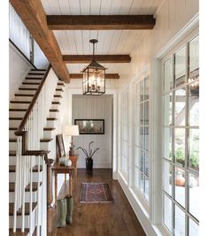 a hallway with wood floors, white walls and wooden railings that lead up to the second floor