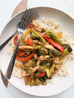 a white plate topped with rice and veggies next to a knife and fork