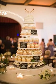 a tiered cake with cupcakes on it at a wedding reception in a banquet hall