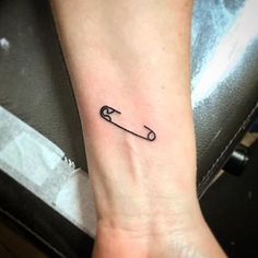 a person with a small tattoo on their wrist holding an object in the shape of a wrench