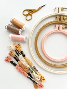 an assortment of sewing supplies including scissors, thread and spools on a white surface