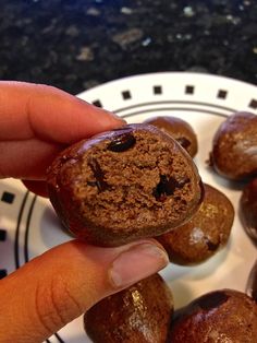 a person is holding some chocolate donuts in their hand