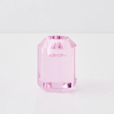 a pink glass bottle sitting on top of a white table