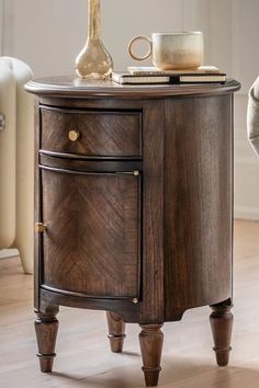 a small wooden cabinet with two drawers on one side and a coffee cup on the other