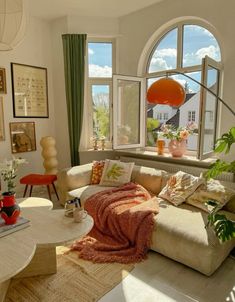 a living room filled with lots of furniture next to a large window covered in plants