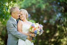 a bride and groom embracing each other in front of trees