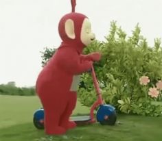 an inflatable red bear riding a blue scooter on top of a lush green field