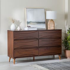 a wooden dresser sitting next to a potted plant on top of a hard wood floor