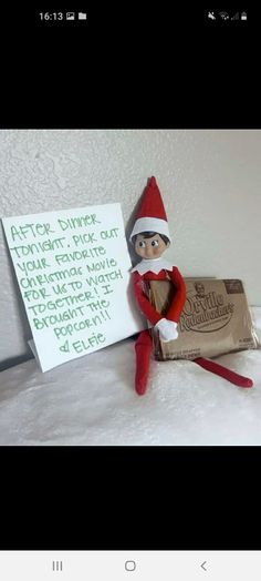 an elf is sitting next to a bar of milk and a note on the wall