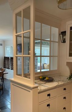 a kitchen with white cabinets and marble counter tops in front of a dining room table