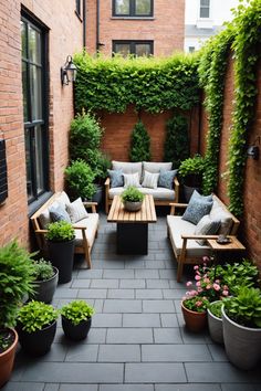 an outdoor seating area with potted plants and couches on the side of a brick building