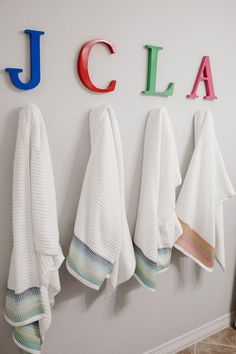 towels are hanging on the wall in front of colorful letters