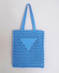 a blue crocheted bag hanging on a wall with the shape of a heart