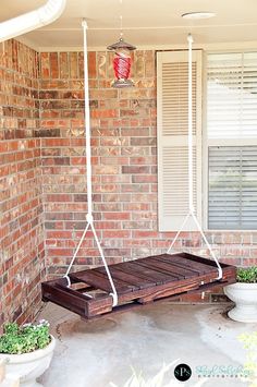 a porch swing that is attached to a brick building