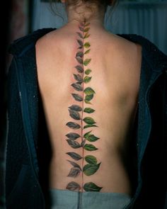 the back of a woman's neck with green leaves on her upper and lower back