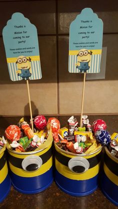 minion birthday party favors in blue and yellow buckets with candy candies on top