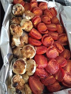 there are many different types of food in the trays on the table, including tomatoes and mushrooms