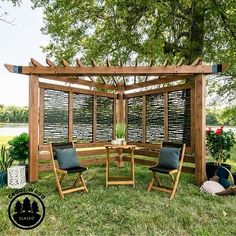 a wooden pergolan with two chairs and a table in the grass next to it