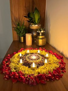 an arrangement of flowers and candles on a wooden table in the middle of a room