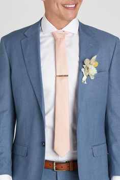 a man in a blue suit with a pink tie and flower boutonniere