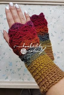 a woman's hand wearing a multicolored knitted mitt with texting on it