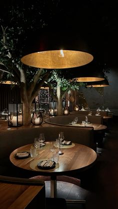 a dimly lit dining room with wooden tables and chairs in front of a tree at night