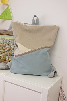 three different colored pillows sitting on top of a white cabinet next to a painting and kites