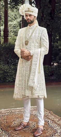 a man standing on top of a rug wearing a white suit and hat, with his hands in his pockets