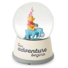 a snow globe with winnie the pooh riding on a blue horse and saying, our adventure begins