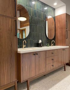 a bathroom with wooden cabinets and two mirrors on the wall, along with marble counter tops