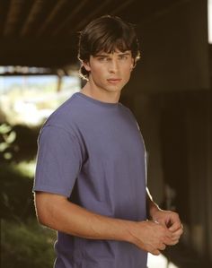 a young man in a blue t - shirt is posing for a photo with his hand on his hip