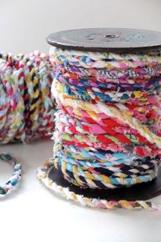 spools of multicolored yarn sitting on top of a white table next to a spool of thread