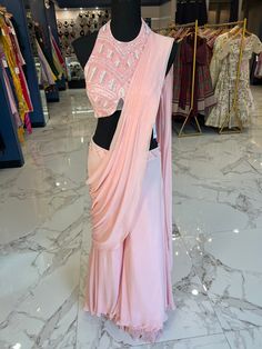 TO ORDER LARGER SIZES, PLEASE WHATSAPP +1 (945) 444-2194 pastel pink handwork Ready saree accentuated with pearl and bead work . Crafted with a halter neckline and a flattering backless design paired with a trendy palazzo style bottom and attached pleats Slight variation in color is possible due to digital photography. Shipping will take 2 weeks,Please WHATSAPP +1 (945) 444-2194 for more info. Pink Party Wear Pre-draped Saree With Mirror Work, Pink Embellished Pre-draped Saree For Diwali, Semi-stitched Embellished Pink Pre-draped Saree, Pink Embellished Pre-draped Saree For Wedding, Traditional Pink Embellished Pre-draped Saree, Pink Party Wear Pre-draped Saree With Pallu, Pink Embellished Saree With Traditional Drape, Pink Pre-draped Party Wear Saree With Pallu, Pink Pre-draped Saree With Mirror Work For Party