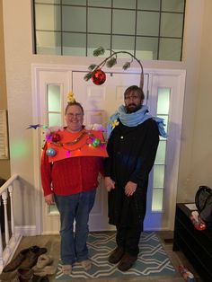 two people standing in front of a door with decorations on their heads and sweaters