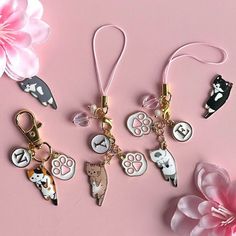 four keychains with different animal designs on them next to pink flowers and petals