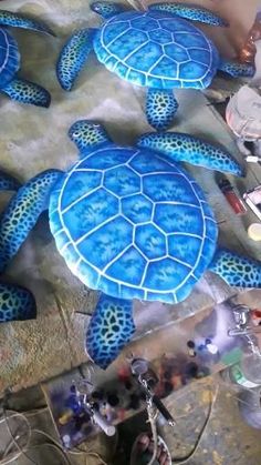 two blue turtles sitting on the ground next to some other items in front of them