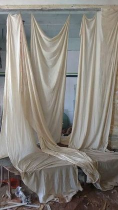 an unmade bed with drapes hanging from it's sides in a room