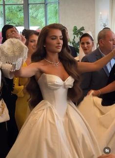 a woman in a wedding dress is dancing with other people behind her at a party