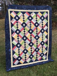 a quilt on the grass with trees in the background