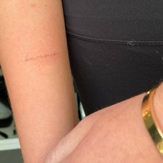 a woman's arm with the word love written on it, and a gold bracelet