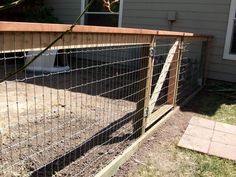 a fence that is next to a house in the yard with grass and dirt around it