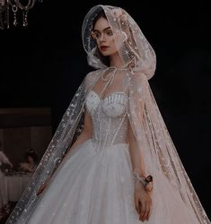 a woman in a wedding dress with a veil on her head is standing next to a chandelier