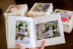 an open book with photos on it in someone's hand and four other books behind them