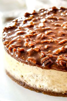 a cheesecake covered in chocolate and nuts on a white plate